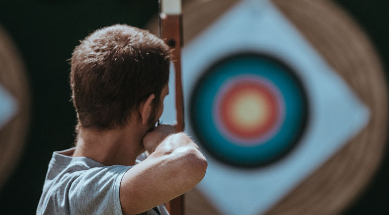 a person aiming a bow and arrow at a target